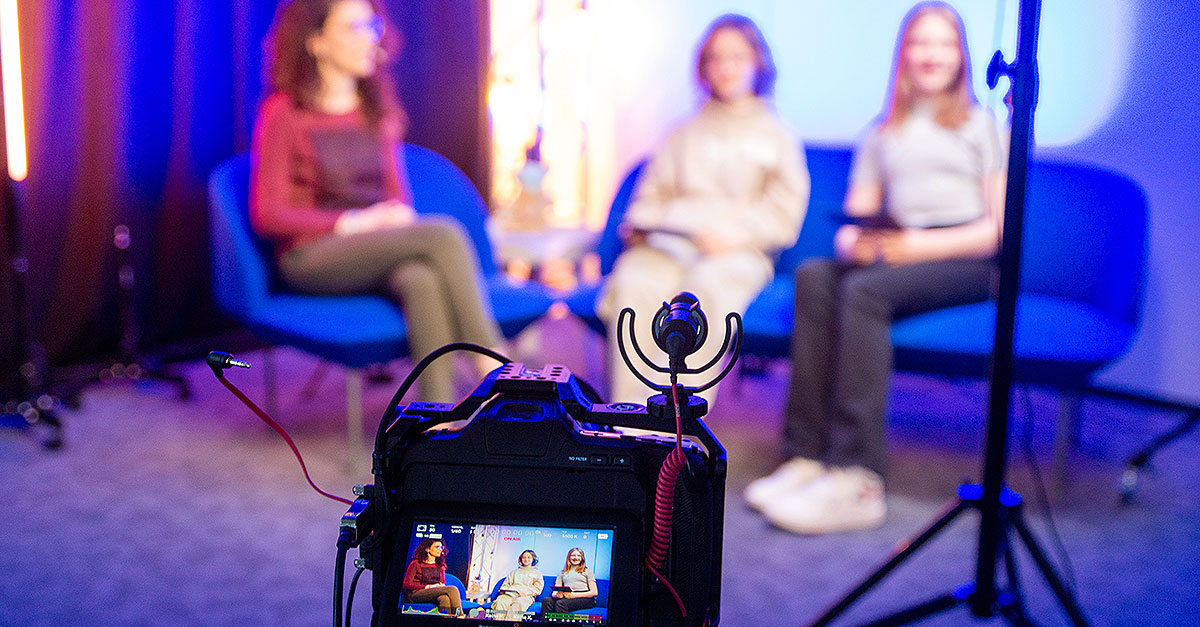 Image of an interview setting in front of a camera on Girls' Day, showing two girls interviewing one female employee: Working in IT is fascinating and versatile — and there are numerous ways to start a career
