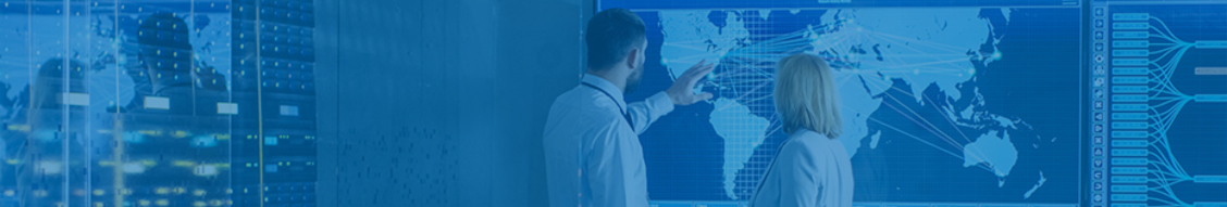 Two people in business attire stand before a large digital world map, with one pointing at it, highlighting a discussion on data analysis or global strategy to ensure business continuity.