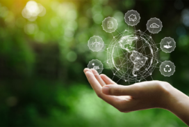 A hand holds a digital globe with sustainable energy and environmental icons floating around it, symbolising global sustainability and technology.
