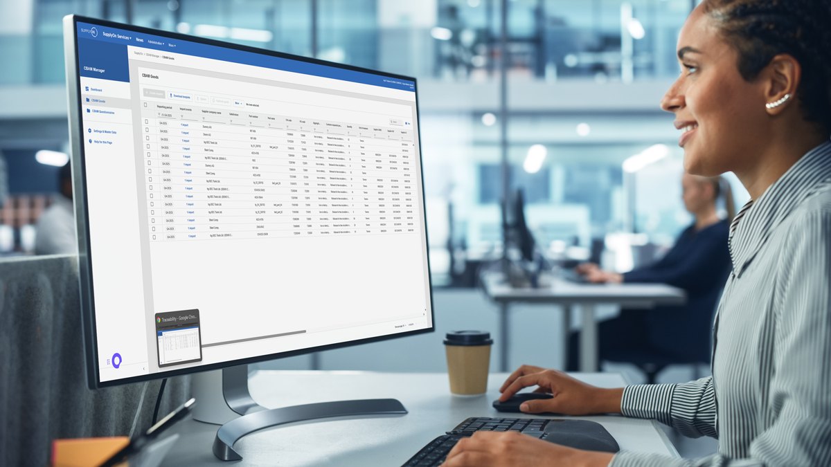 A person sits at a desk using a computer displaying a spreadsheet or database interface in a modern office environment.
