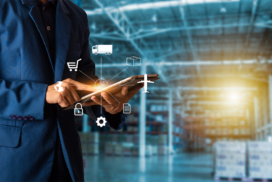Person in a warehouse uses a tablet with digital icons representing logistics and supply chain elements, such as a lorry, aeroplane, and shopping trolley, overlaid on the image.