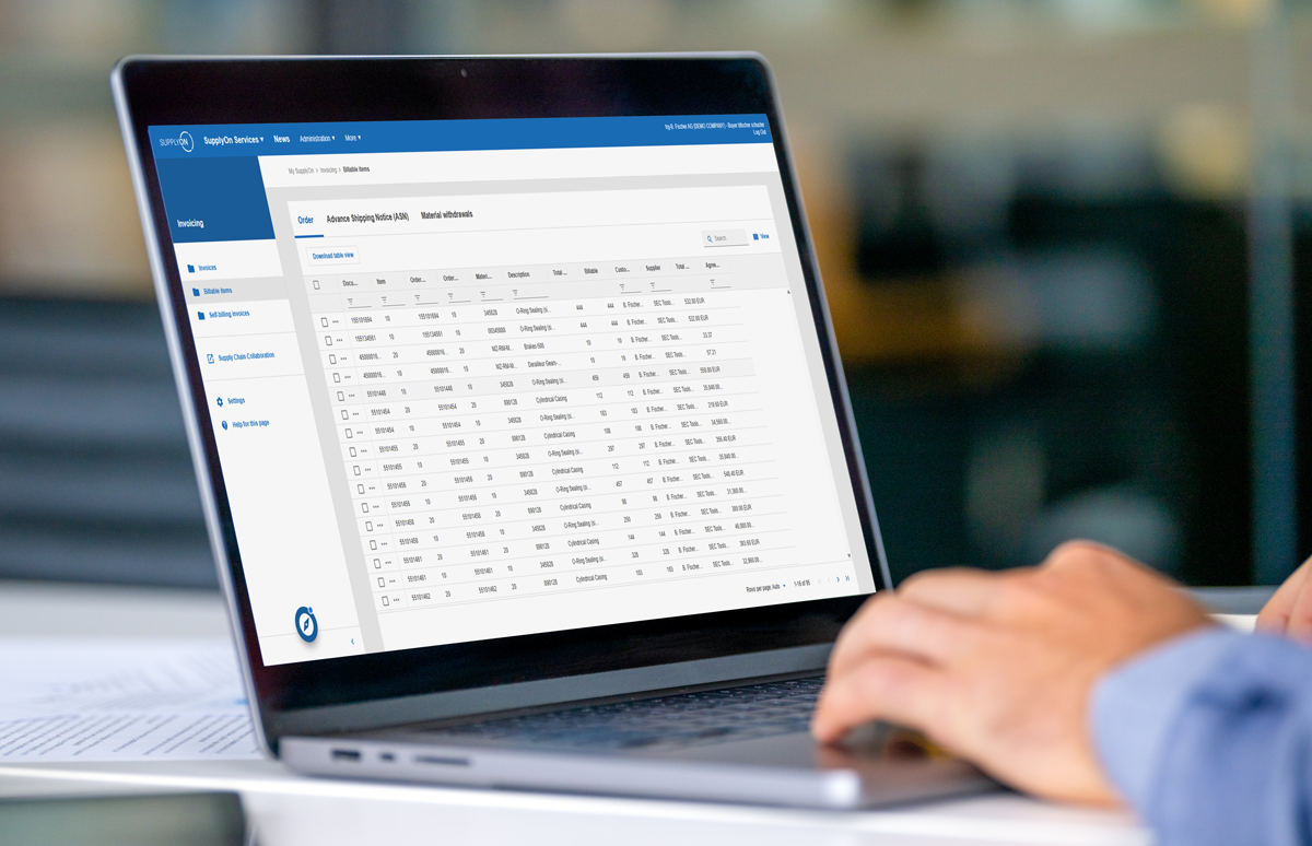 A person using a laptop displaying a data management dashboard with a table of information and navigation menus on the screen.