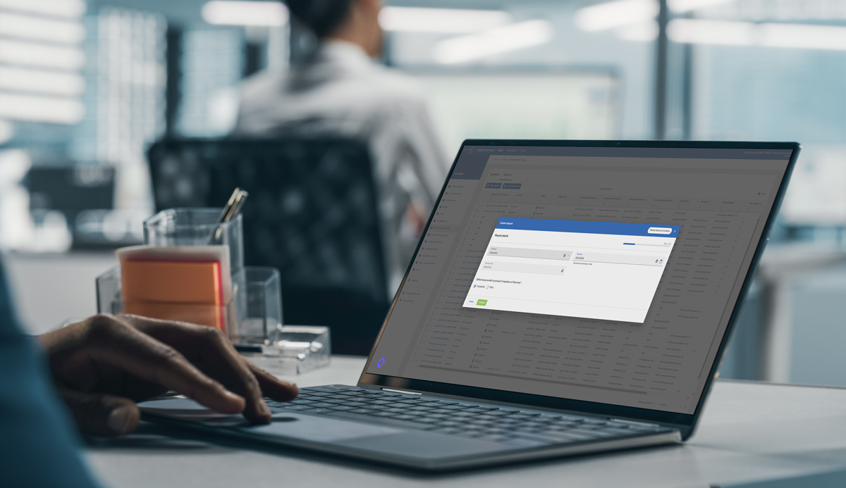 A person using a laptop in an office setting, with a software application window open on the screen.