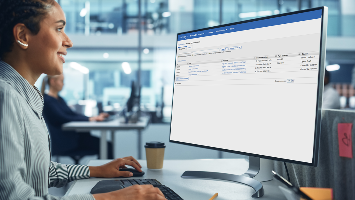 A person sits at a desk in an office, using a desktop computer displaying an Intel Analytics Database web interface.