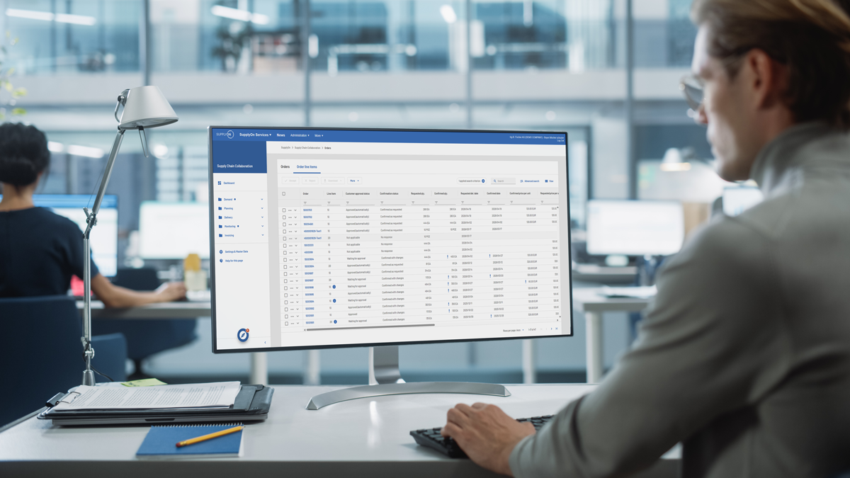 Person working at a desk, looking at a computer monitor displaying a data management or spreadsheet application in a modern office setting.