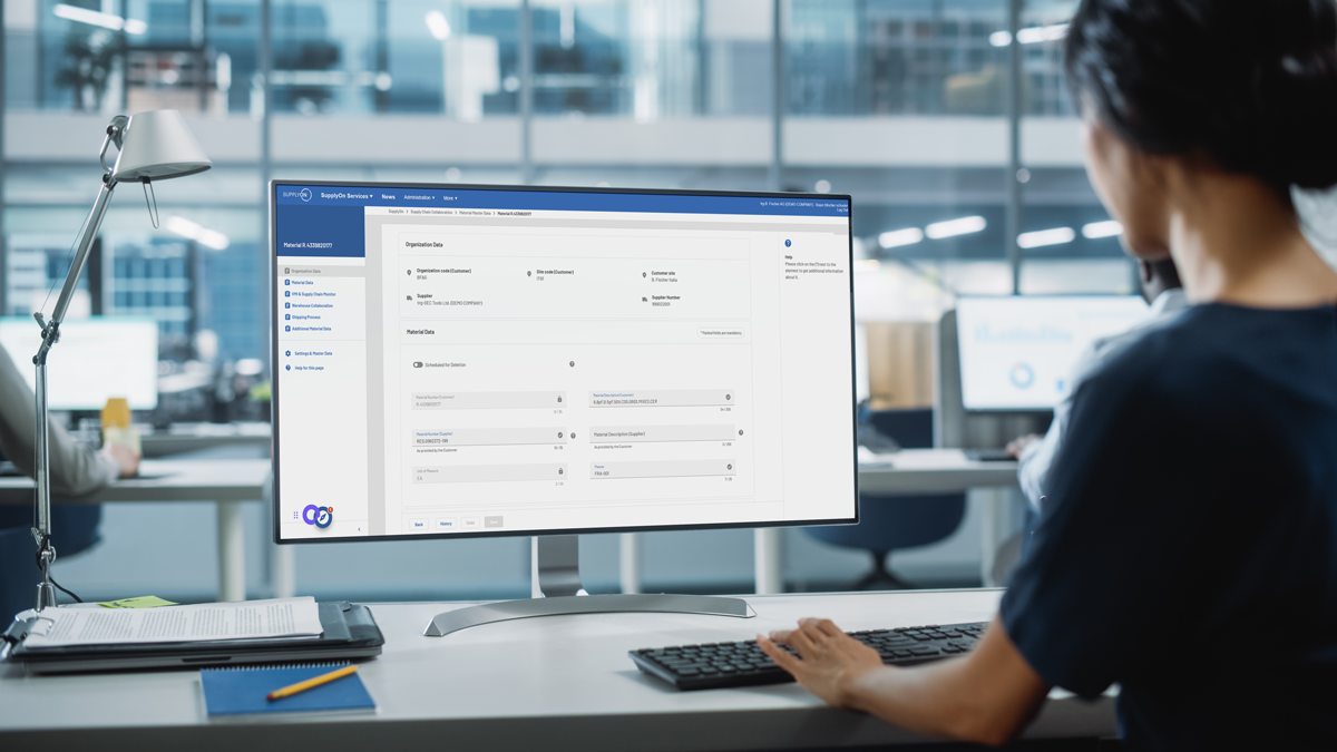 Person working at a desk in a modern office, looking at a large computer monitor displaying a software dashboard with various options and settings.