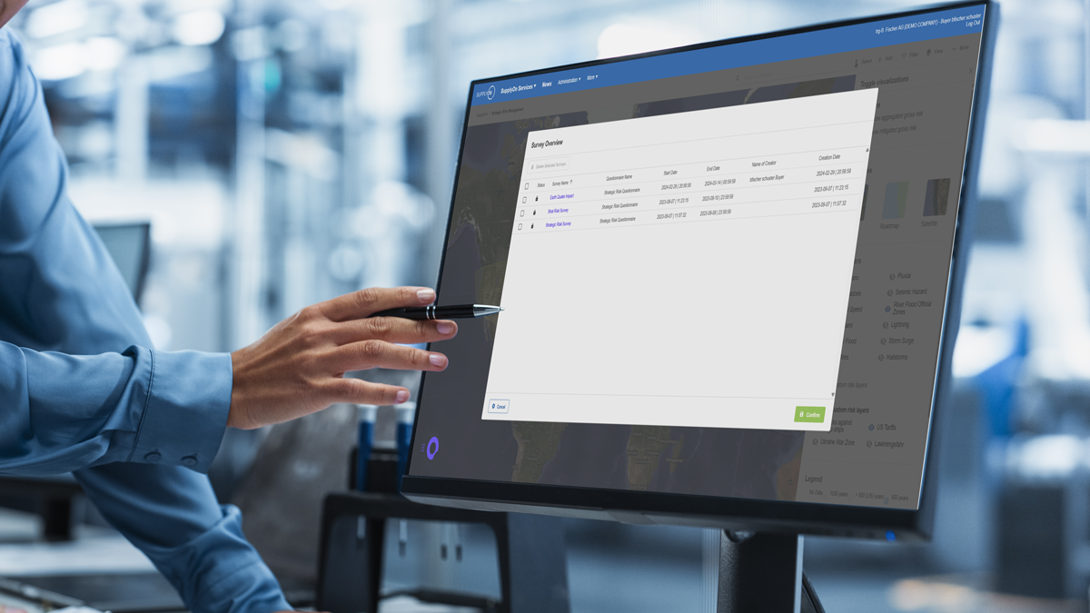 Person pointing at a computer monitor displaying a software dashboard with a list of saved drones and related information in a professional office setting.