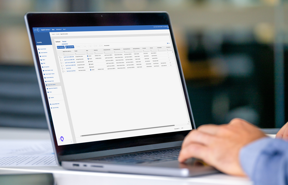 A person uses a laptop displaying a data management or dashboard interface with tables, filters, and navigation menus.