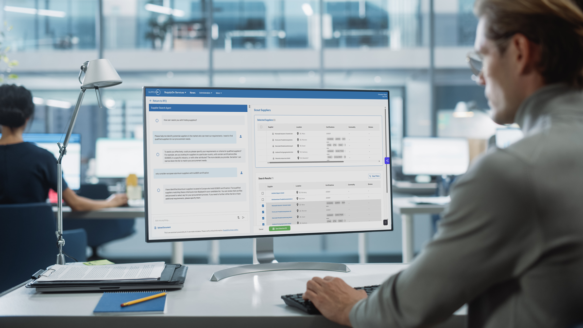 A person working at a desk views data and text boxes on a large computer monitor in a modern office setting.