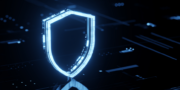 A glowing blue shield icon stands on a dark digital background, symbolising cybersecurity or data protection.